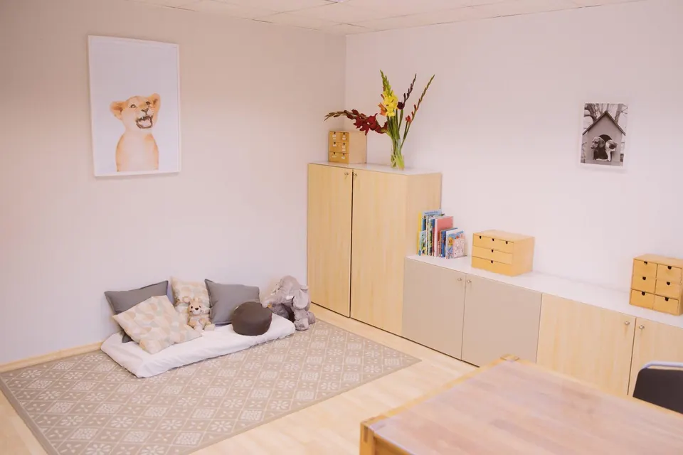 Ruheecke im Therapieraum mit Matratze, Kissen und Kuscheltieren auf einem hellen Teppich