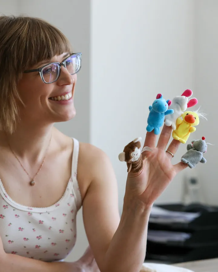 Logop&auml;din am Therapietisch mit bunten Fingerpuppen an der Hand